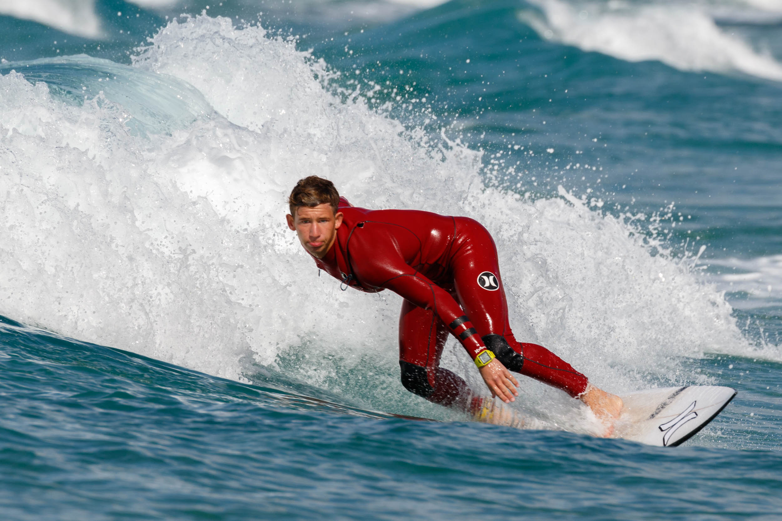 Surfer in a red wetsuit carving a wave